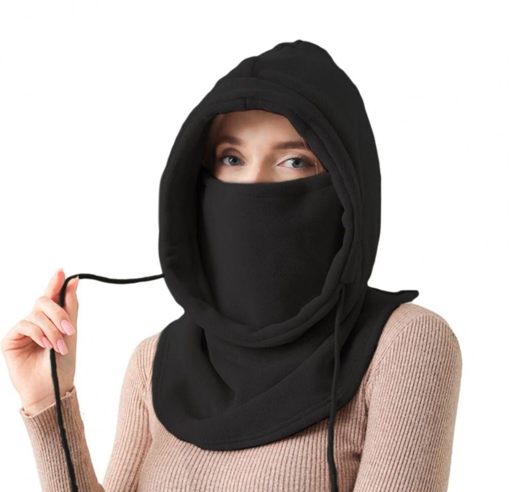 "A woman wearing a black balaclava that covers her head and face, leaving only her eyes visible; the scarf portion hangs around her neck."
