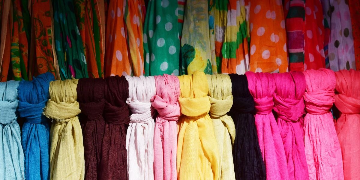 Colorful scarves in a variety of patterns and textures displayed in a row, perfect for all seasons.