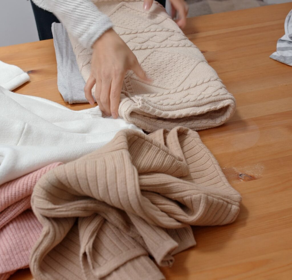 A close-up of a silky scarf being gently hand-washed, with soft bubbles in a basin and the fabric draped over a tiled edge.