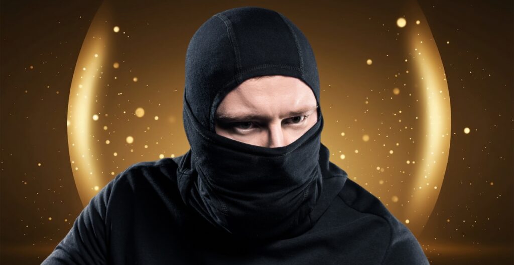 A person wearing a black balaclava and dark clothing, with only their eyes visible. The background features warm golden-brown tones and decorative light orbs.