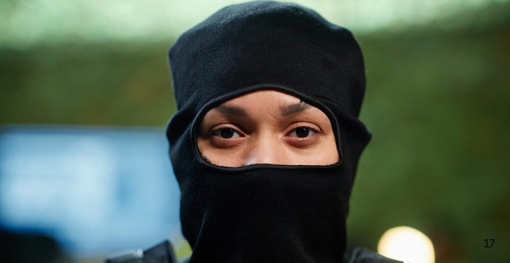 A person wearing a black balaclava with only their eyes visible.