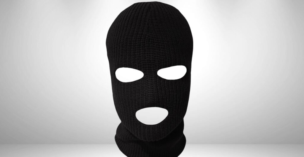 A black balaclava covering the head and face with openings for the eyes and mouth, set against a light gradient background.