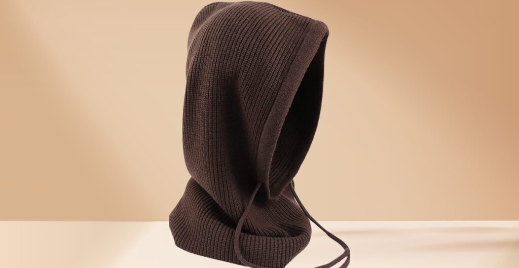 A dark brown knit balaclava with a hood and long drawstrings sits against a neutral beige background.