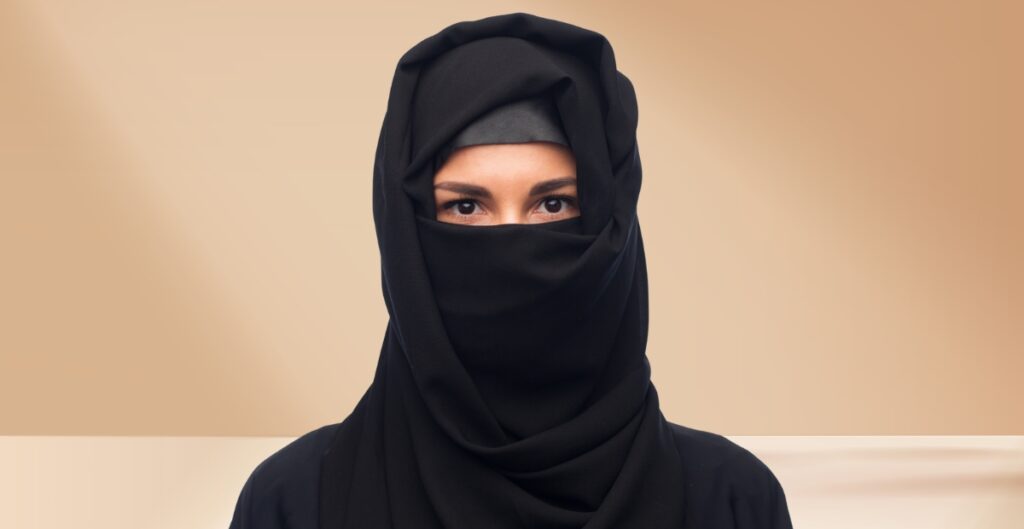 A woman wearing a black hijab that covers her hair and neck, with only her eyes visible.