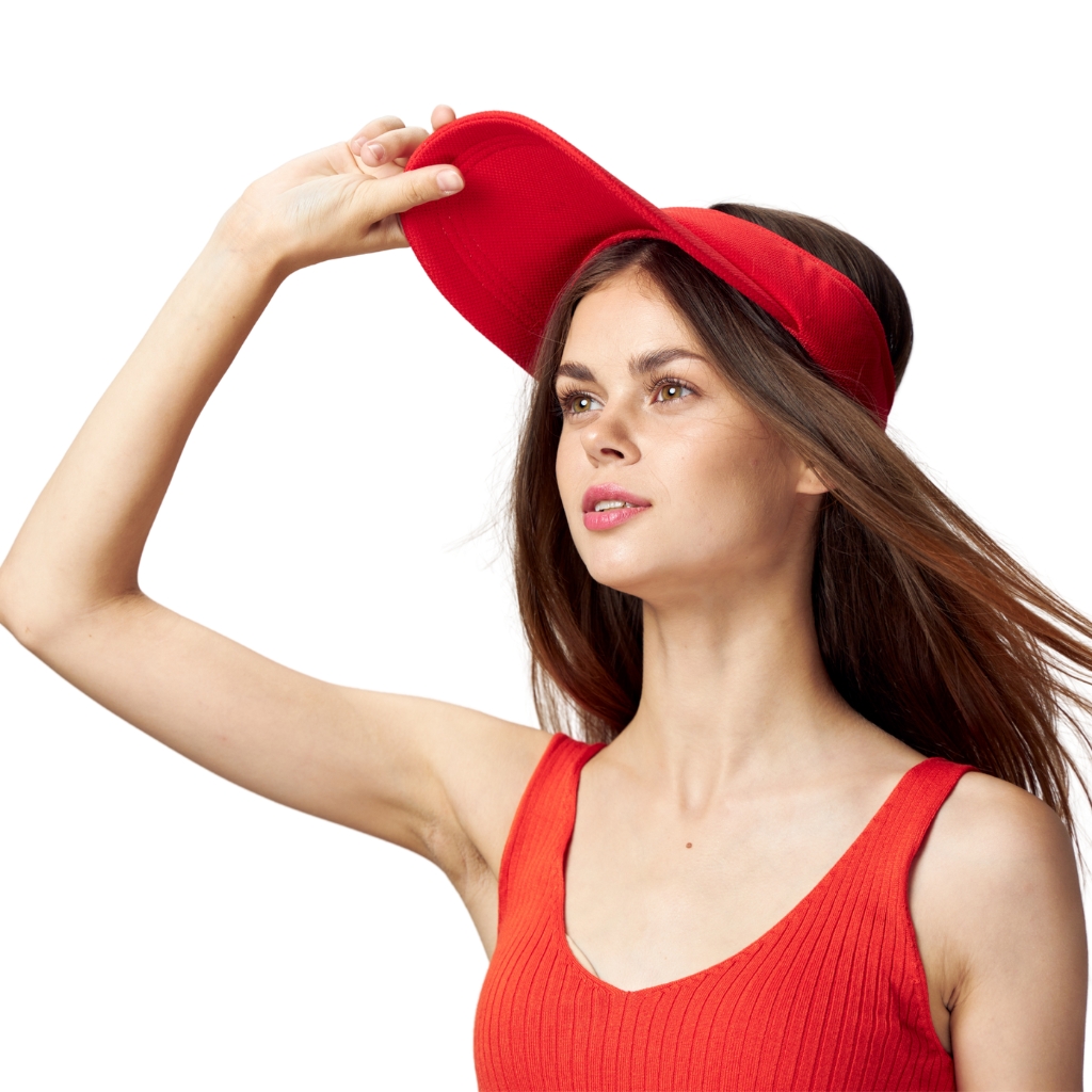 "A young woman wearing a red sleeveless top and a red visor, adjusting the visor with her right hand against a white background."
