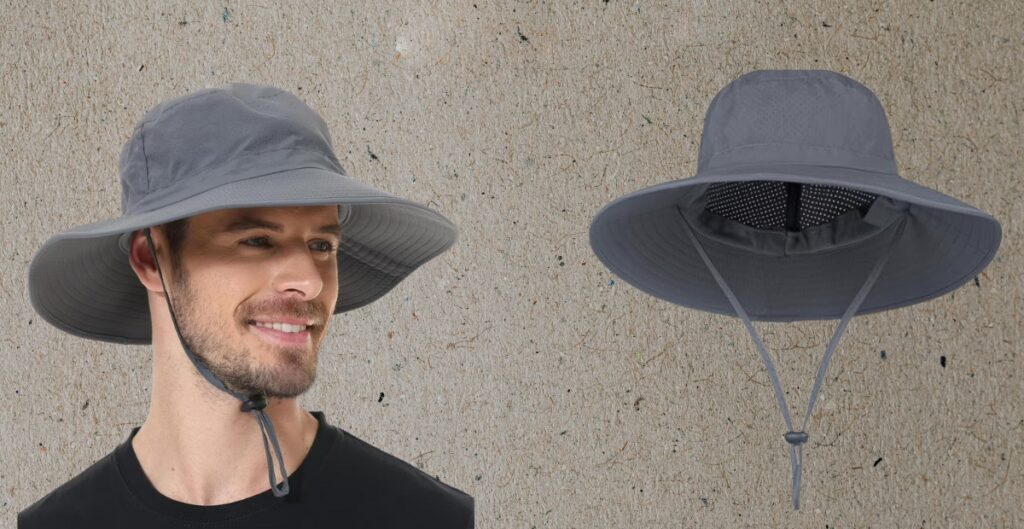 Alt-Text (kurz, beschreibend): Ein Mann mit einem grauen Sonnenhut mit breiter Krempe und Kinnriemen, lächelnd. Neben ihm liegt ein passender Hut mit Nackenkordel.
