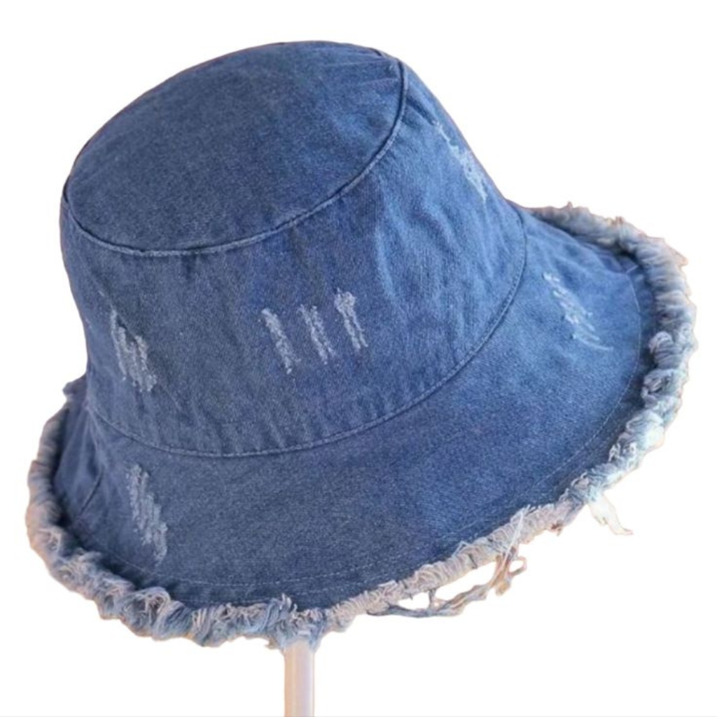 A blue denim bucket hat with a frayed edge on the brim, displayed on a stand.