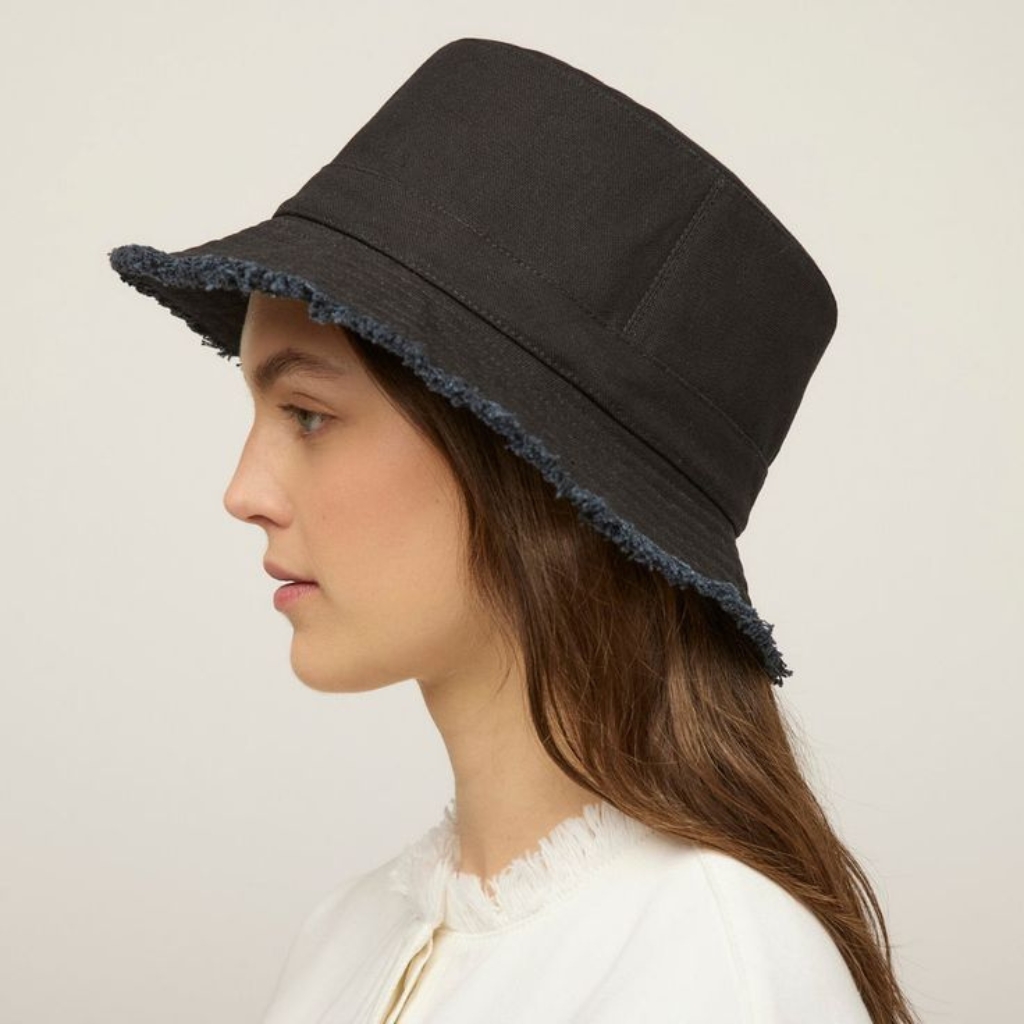 Side view of a black hat with a frayed denim-like edge, worn by a woman with long brown hair