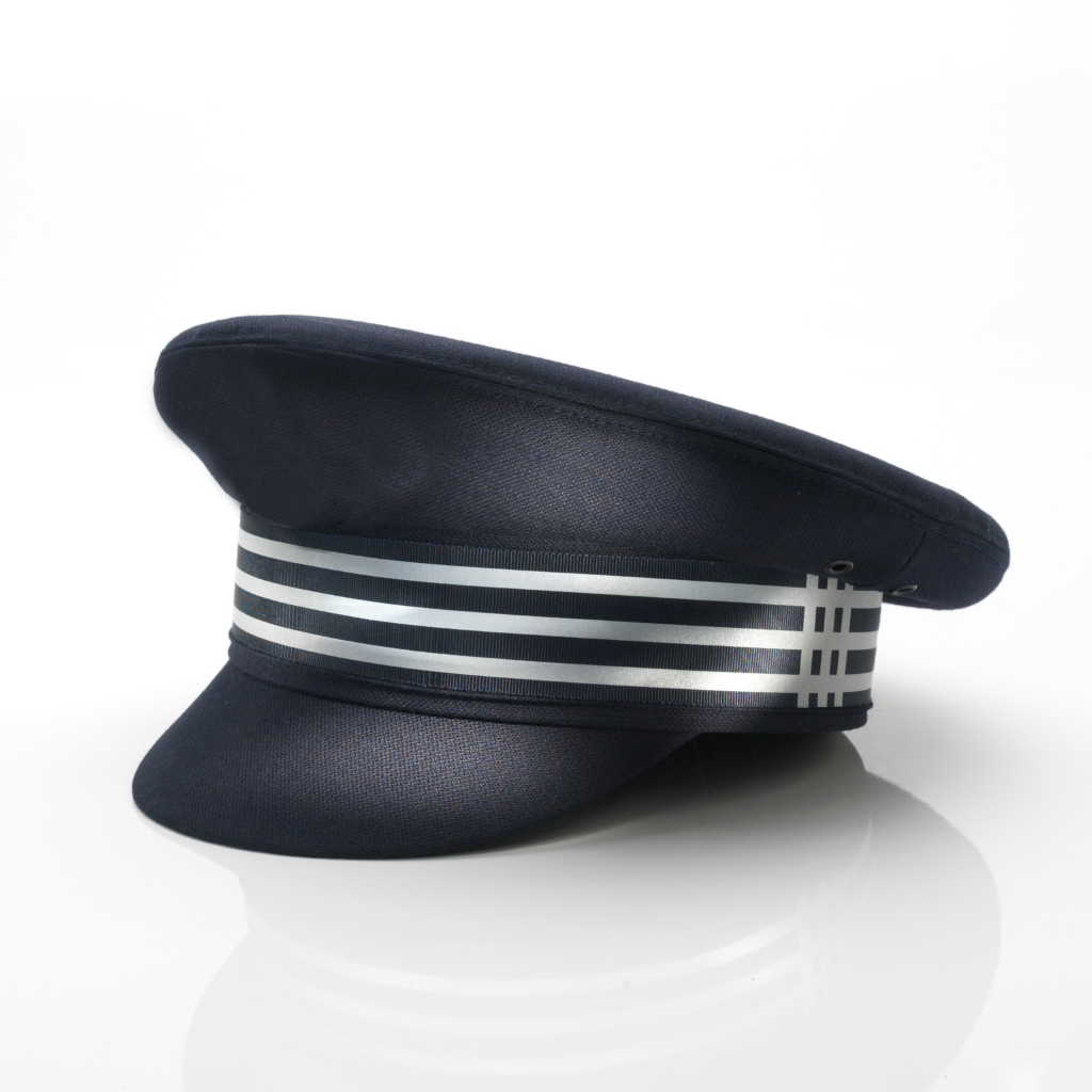 A navy captain’s hat with a white-and-silver striped band, navy crown, and a slim visor, resting on a white reflective surface.


