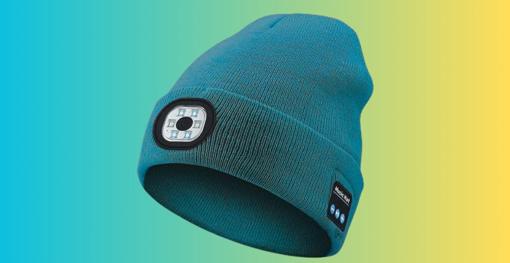 Turquoise knit beanie with a small square LED light embedded on the front and a fabric label on the side, set against a gradient teal-to-yellow background.