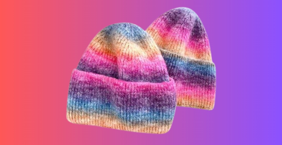 Two knit beanies with an ombre rainbow gradient from pink to purple against a pink-to-purple gradient background