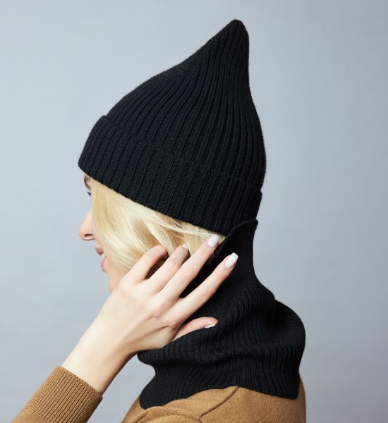 Black balaclava hat and caps arranged on a wooden table, showcasing winter headwear.