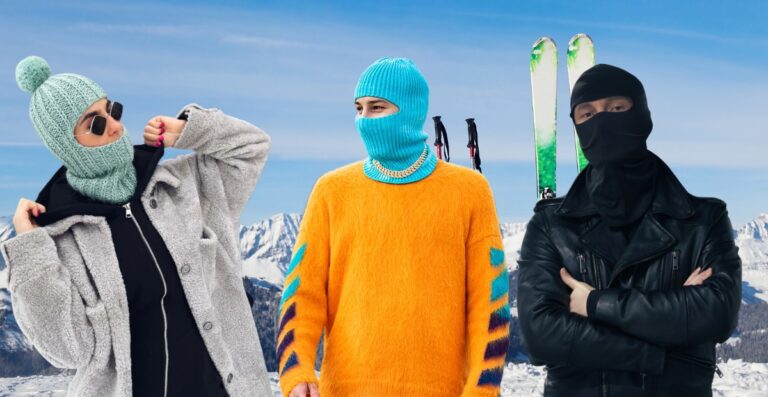 Frau in einer farbenfrohen Sturmhaube und einem Trenchcoat lächelt auf einer verschneiten Straße und präsentiert winterliche Streetwear-Mode.