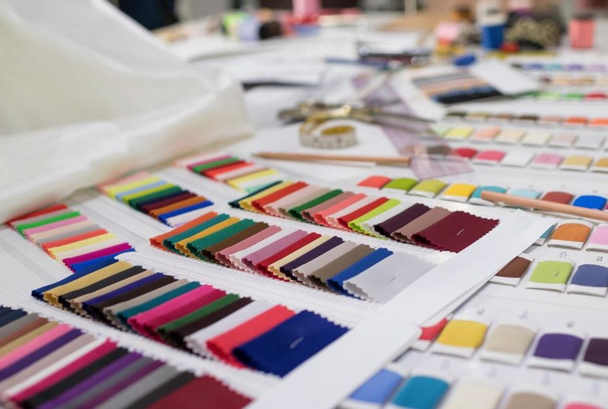 A close-up view of a table with various color swatches, fabric samples, and paint palettes, arranged in rows for selection or comparison.
