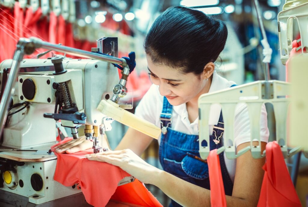 A professional manufacturing facility producing custom balaclavas, featuring machinery and workers customizing fabric coverings.