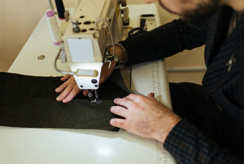 Un tailleur coud un tissu sur une machine à coudre industrielle