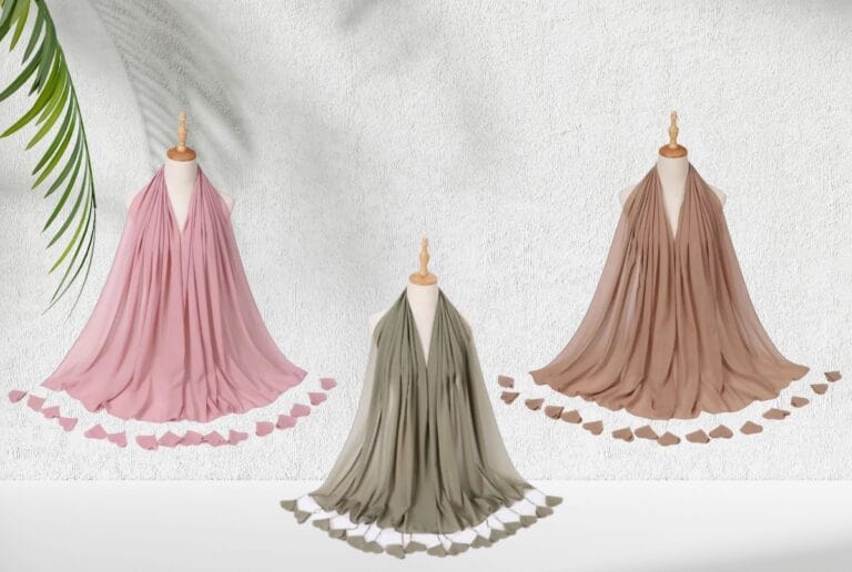 Pink, olive and taupe chiffon hijabs with tasselled edges on three display stands