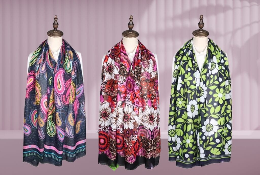 Tres pañuelos de viscosa con estampados de cachemir, flores rojas y hojas verdes en expositores