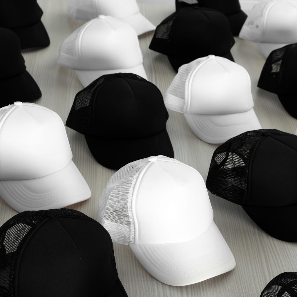 Several white and black trucker caps laid out in a pattern, showing front panels and mesh backs.