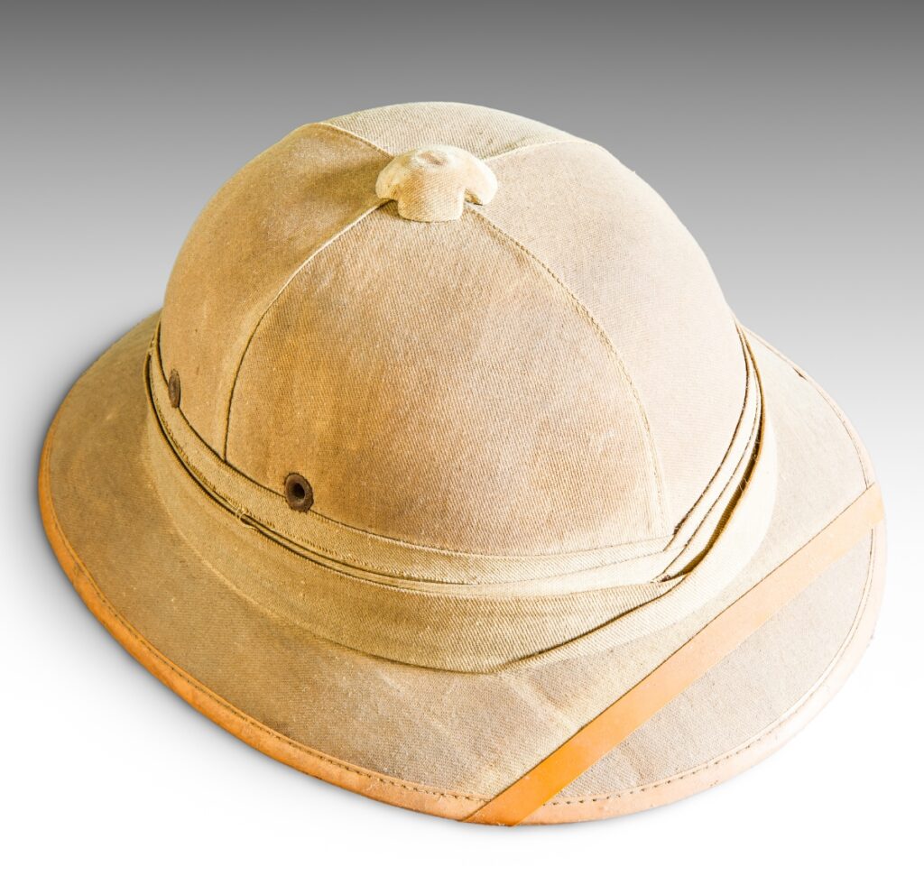 “Beige pith helmet-style hat with a tan leather band and stitched seams, photographed against a gray gradient background.”