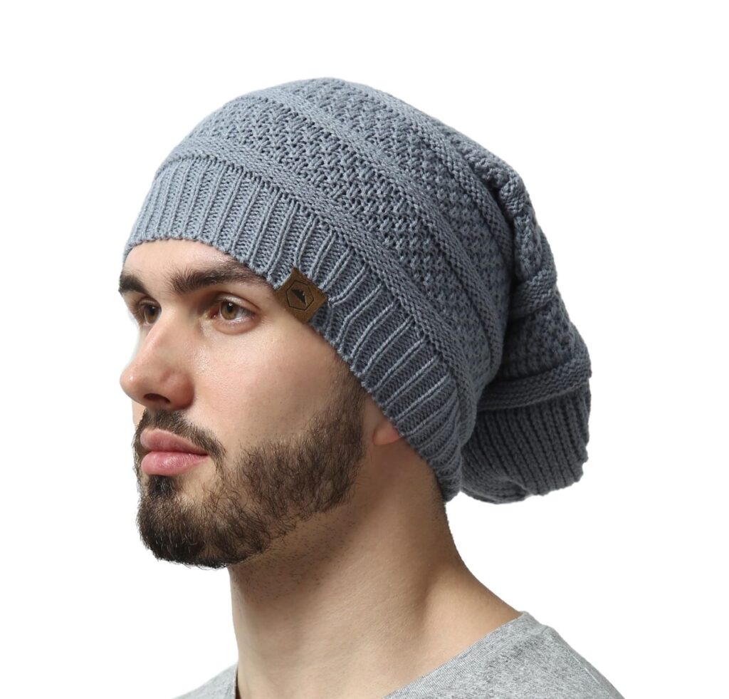 A man wearing a soft, gray knit slouchy beanie with a textured pattern and a small leather logo patch on the front. Custom Slouchy Beanies Manufacturer