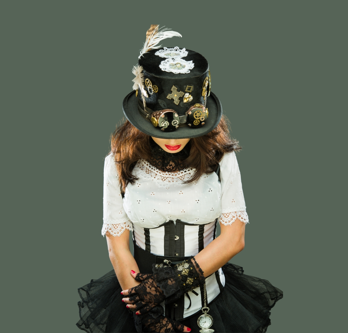 A person wearing a black steampunk top hat adorned with gears, lace, and a feather, paired with a white lace top and black corseted skirt.