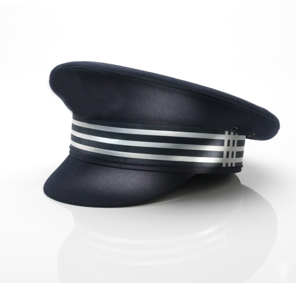 A navy captain’s hat with a wide black brim and a metallic silver double-band around the base, resting on a glossy white surface.
