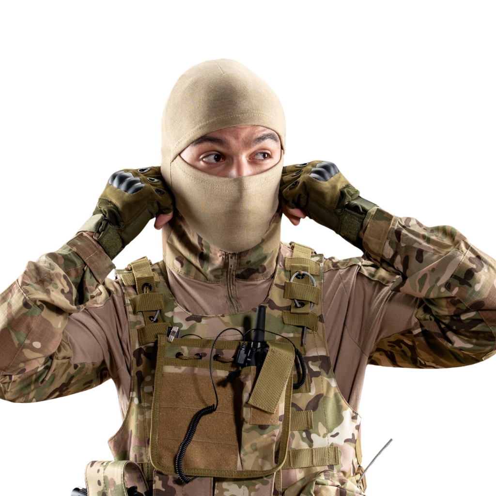 Eine Person in voller militärischer Tarnkleidung, die eine beige Sturmhaube trägt, die Kopf und Gesicht bedeckt und nur die Augen sichtbar lässt, und die den Riemen der Sturmhaube justiert.