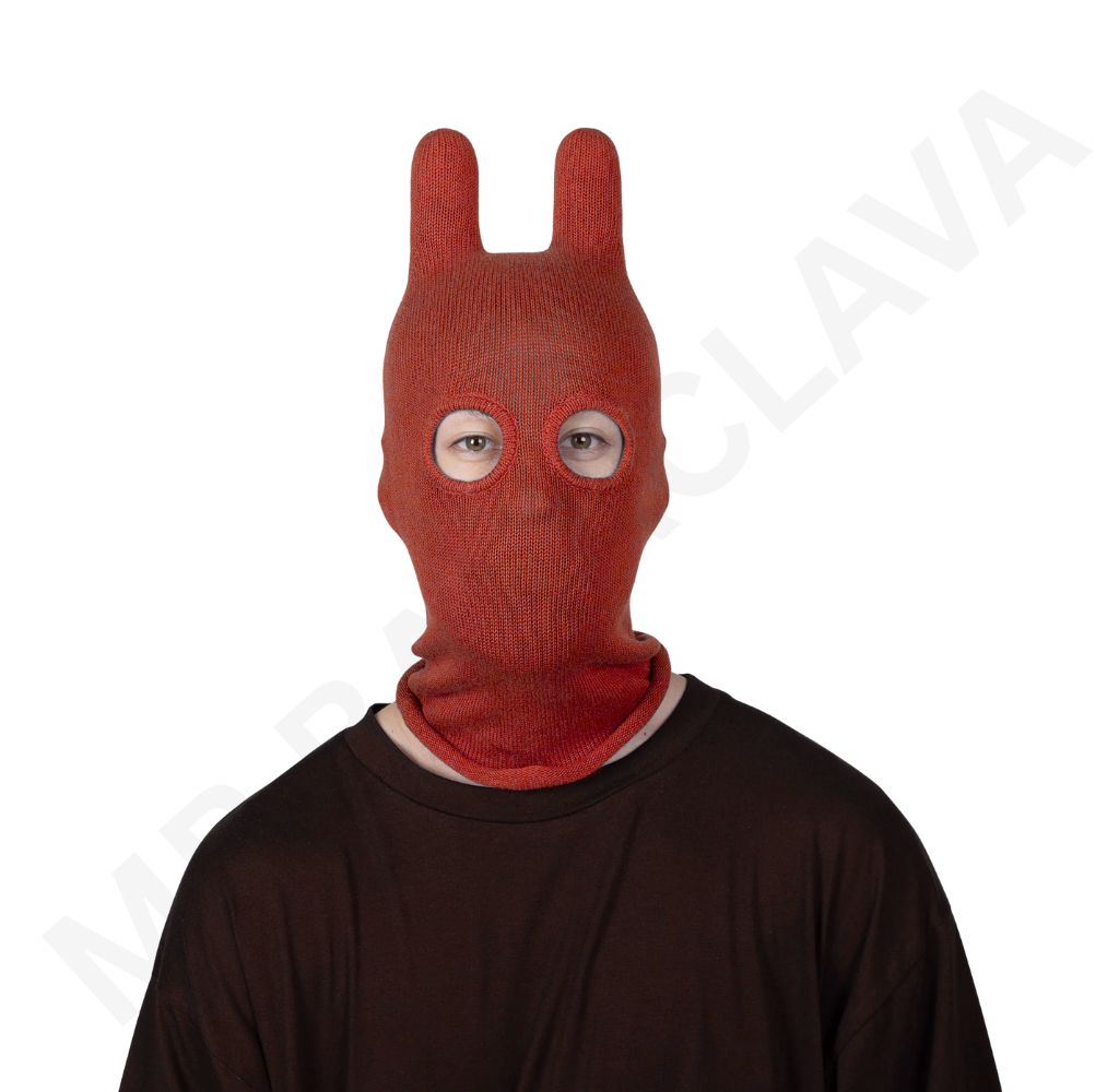 Person wearing a red knitted balaclava with two tall bunny-ear shapes and round eye openings.