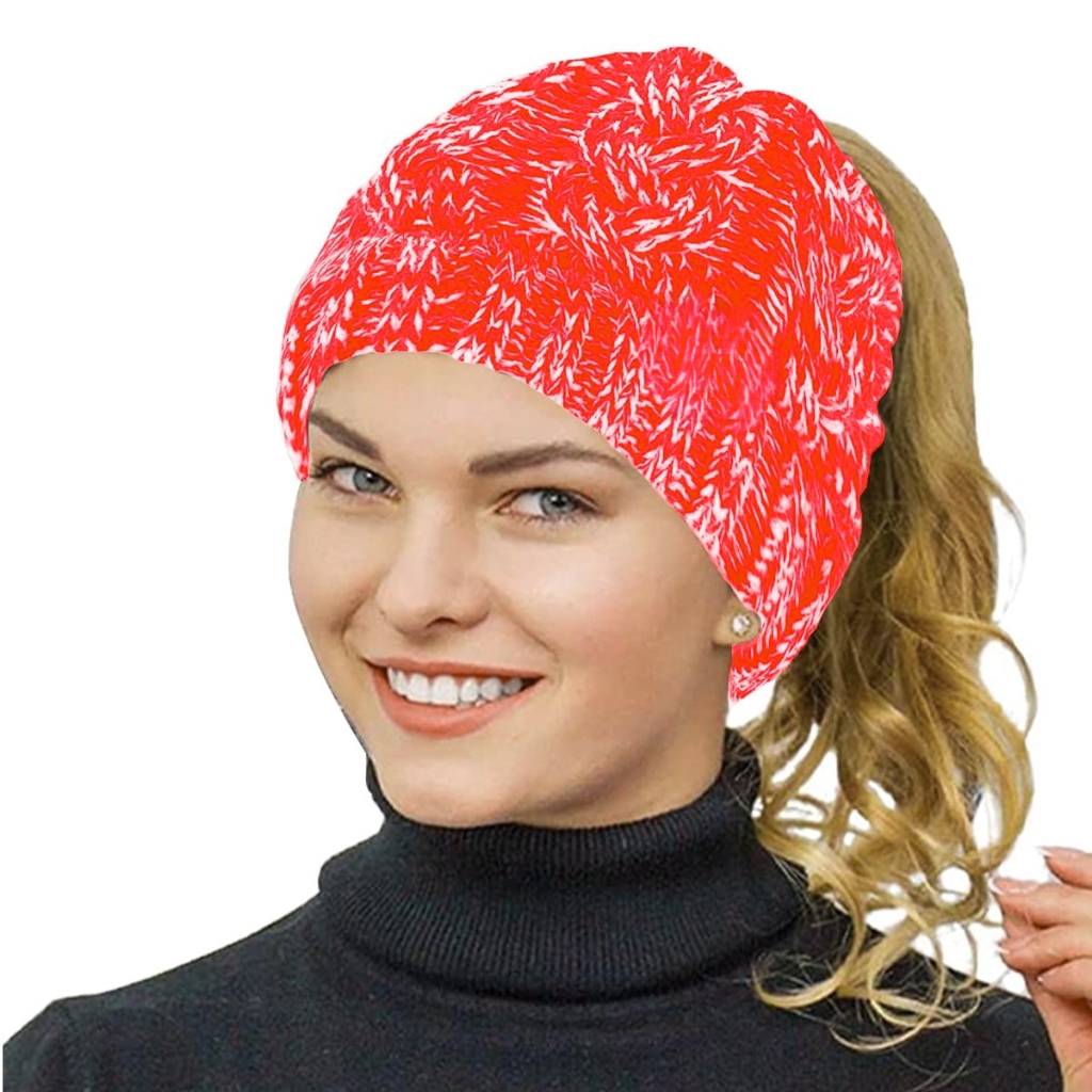 A stylish red and white patterned knit beanie with a built-in opening at the back for a ponytail. The beanie covers the top of a smiling woman with light skin and blue eyes, wearing a black turtleneck.