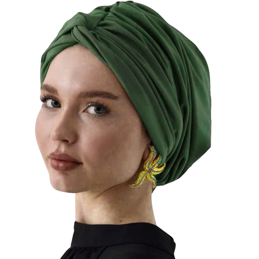 A stylish woman wearing a rich emerald green turban beanie and a bold zigzag yellow earring, facing slightly to the left with a soft smile. Custom Turban Beanie Manufacturer