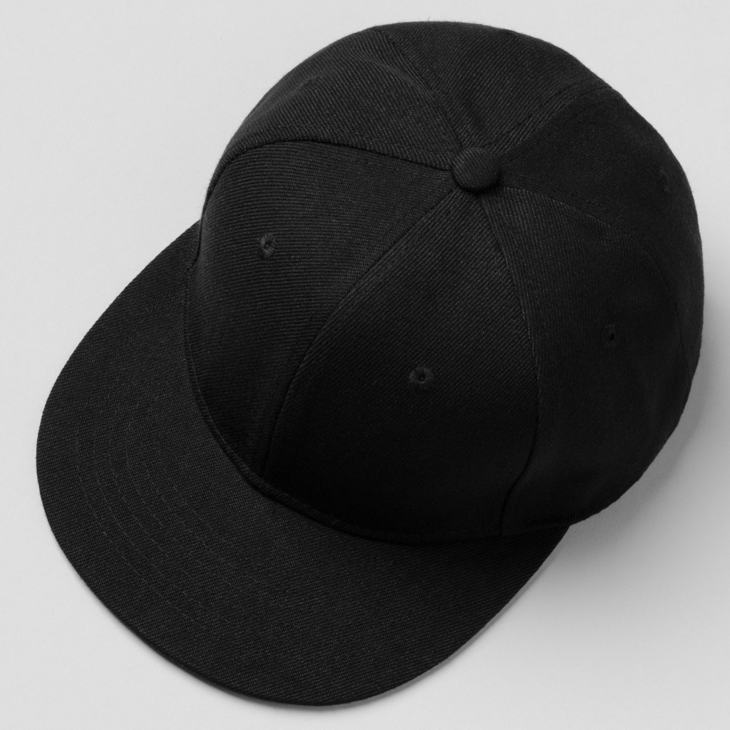 Eine schlichte schwarze Passformkappe, von einem leicht erhöhten Seitenwinkel aus auf einem hellen Hintergrund betrachtet.
