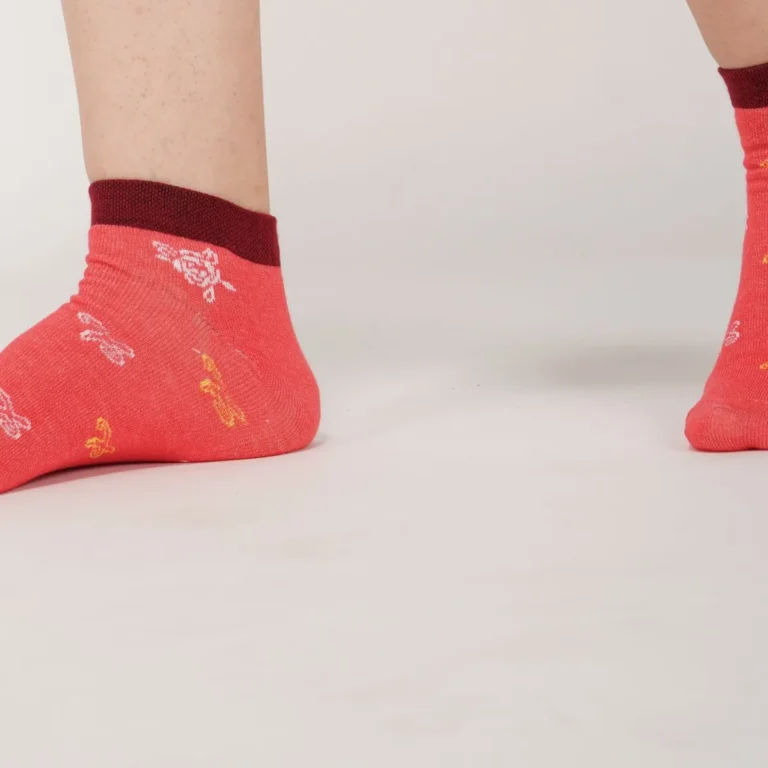 Beine in roten Jacquard-Sneakersocken mit dunkelrotem Bündchen