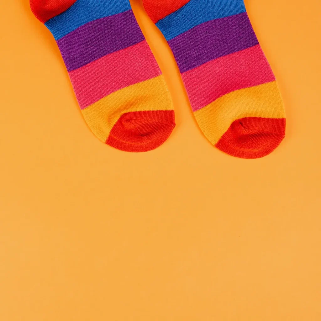 Pair of colour-block socks with purple, pink and orange bands on an orange background