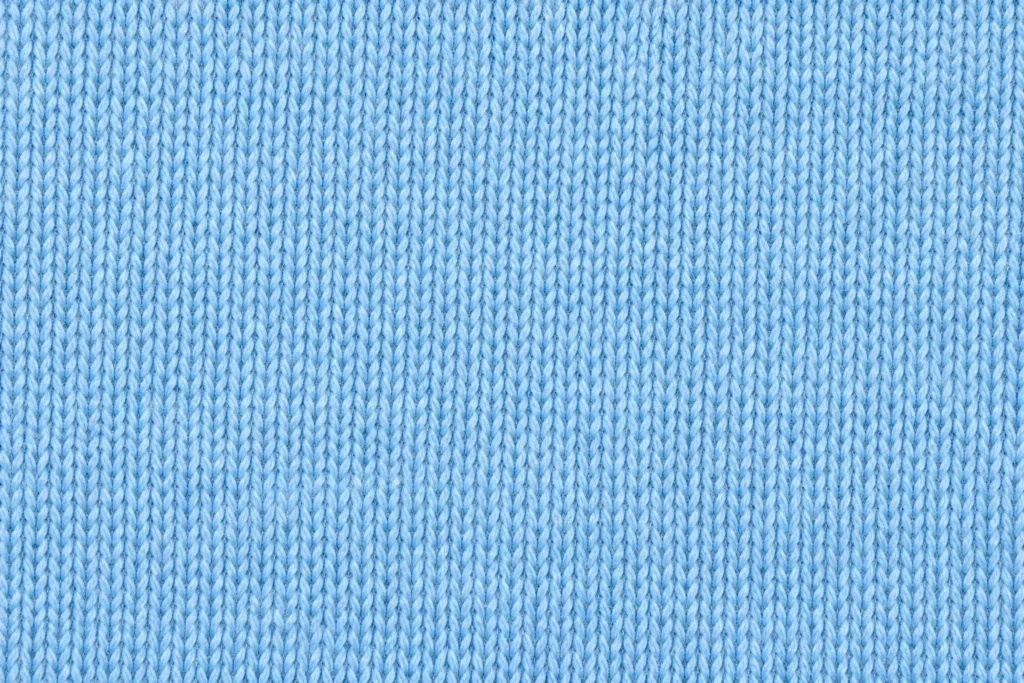 Primer plano de punto jersey de algodón ligero azul cielo con puntadas finas