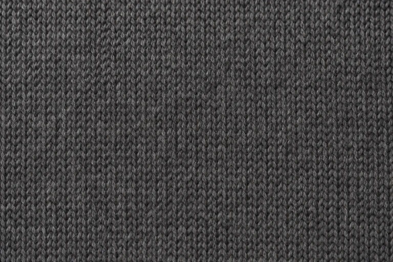 Close-up of charcoal merino wool jersey with fine stitches and a soft halo