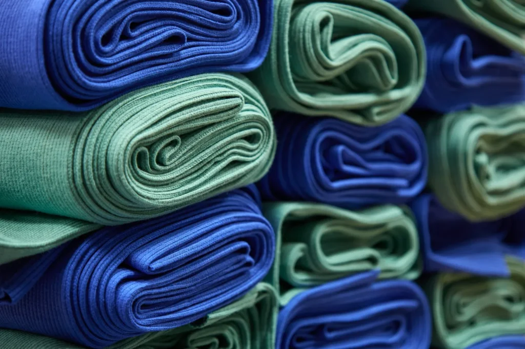 Rollos de tejido azules y verdes apilados en filas