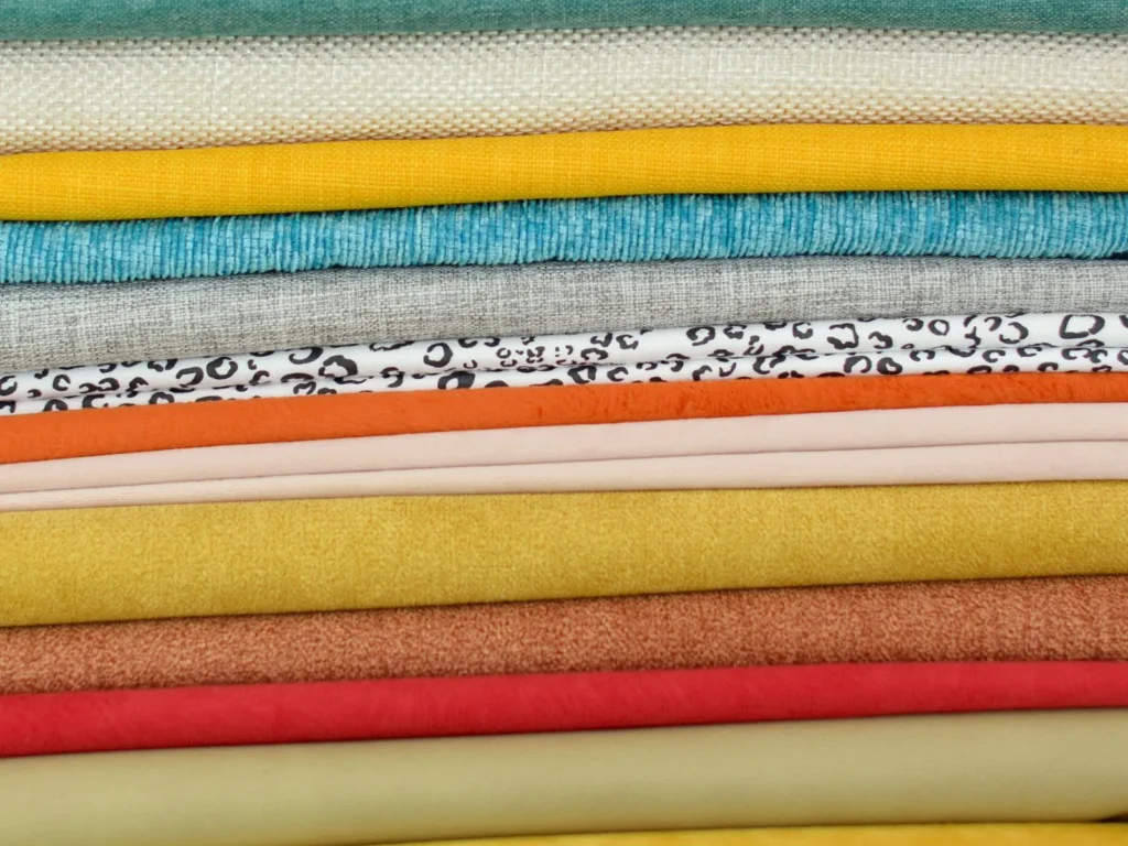 Stack of folded fabrics in many colours, seen from the side