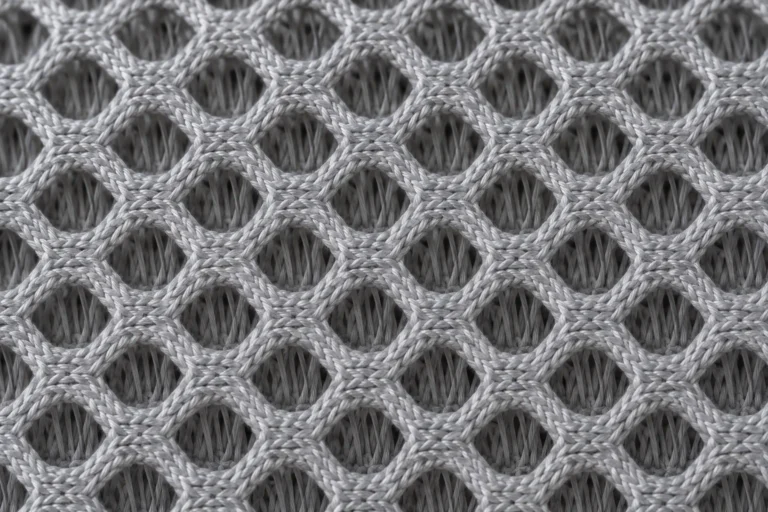 Close-up of grey 3D spacer mesh with hexagonal holes and visible depth