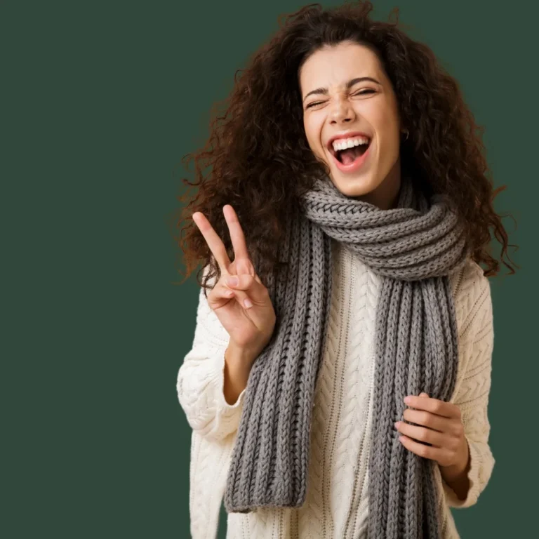 Mujer con una bufanda larga gris de canalé de punto grueso sobre un jersey de ochos crema