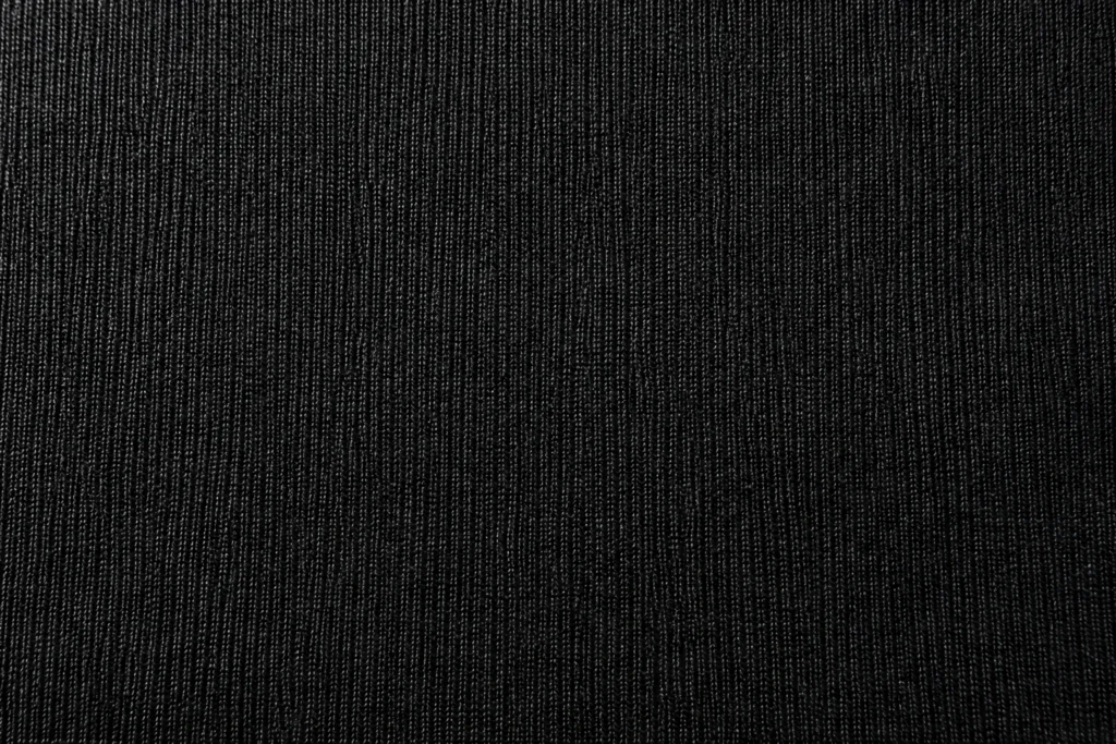 Polyester-Trikot (Kettenwirkware): Nahaufnahme von schwarzem Polyester-Trikot mit feinen Maschenstäbchen und sanftem Glanz