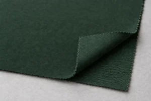 Tejido exterior de poliéster reciclado (rPET): muestra de tejido exterior de poliéster reciclado verde bosque con el revés visible en una esquina doblada