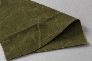Gewachstes Baumwoll-Canvas: olivgrünes Muster aus gewachstem Canvas mit einer dunklen Bruchlinie entlang der Falte